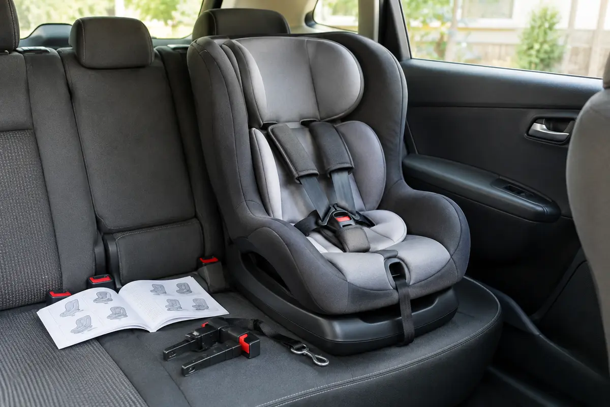 Siège auto bébé vide installé sur une banquette arrière, avec sa notice et ses fixations visibles