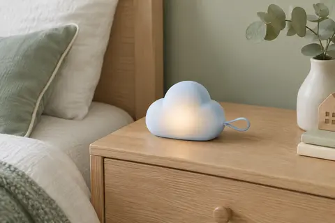 Veilleuse rechargeable Annmore en forme de nuage bleu posée sur une table de chevet en bois clair