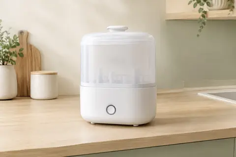 Stérilisateur électrique à vapeur blanc posé seul sur un plan de travail en bois clair