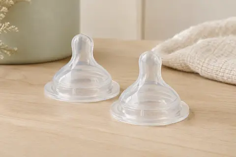 Deux tétines de biberon Avent Natural Response en silicone transparent, posées sur un fond ivoire.