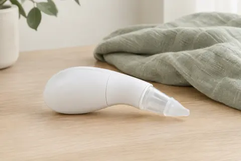 Aspirateur nasal manuel blanc Chicco Physioclean avec embout souple, posé sur une surface en bois clair