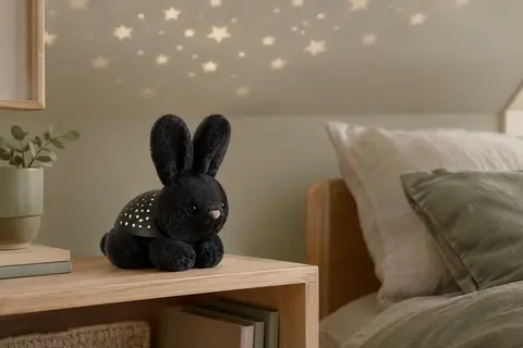 Veilleuse projecteur Benny le Lapin noire posée dans une chambre sobre avec des étoiles au plafond